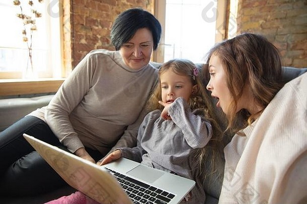 心在<strong>温暖</strong>。幸福的家庭。祖母、母亲和女儿一起度过时光。看电影，使用笔记本电脑，大笑。<strong>母亲节</strong>，庆祝活动，周末，节日，童年的概念。