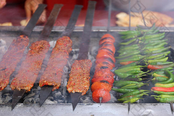 阿达纳烤羊肉串在炭火烤架上用西红柿和青椒烹饪