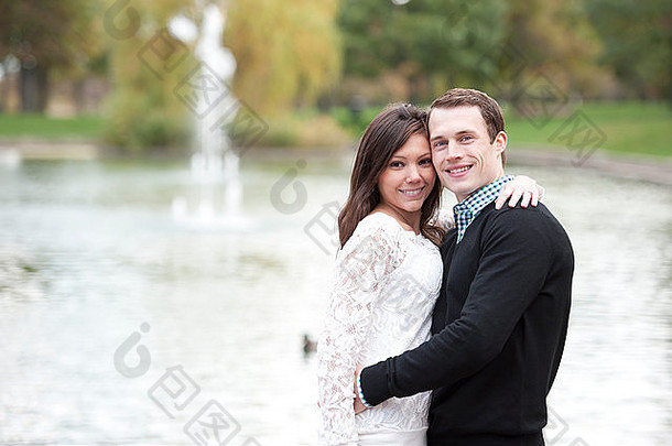 阳光明媚的日子里，一对迷人的<strong>年轻</strong>夫妇在池塘边摆姿势。
