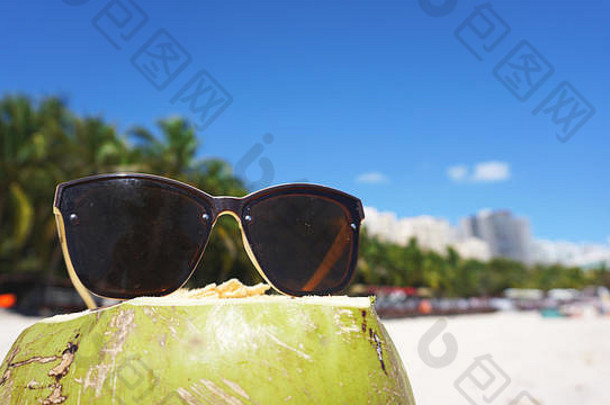 绿色有趣的椰子太阳眼镜白色桑迪海滩夏天旅行概念背景