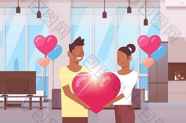 情侣们手持粉色心形情人节快乐概念非裔美国人男女情侣站在一起现代公寓内部彩色气球平放水平