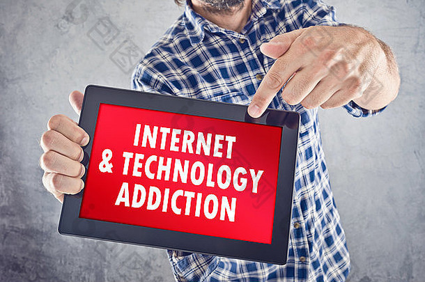 随意的男人指着10英寸的数字平板电脑显示屏，屏幕上显示着互联网和技术成瘾。