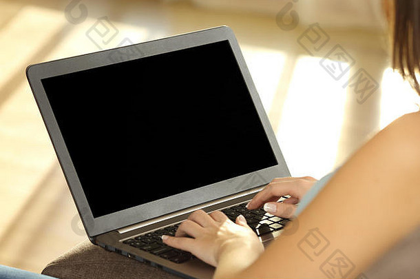 女孩正在使用笔记本电脑，在家里客厅的沙发上展示一个空白屏幕，背景是暖光