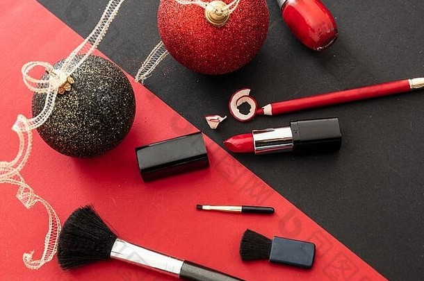 化妆圣诞派对概念，红色和黑色平铺背景。化妆用品及圣诞球、除夕夜准备