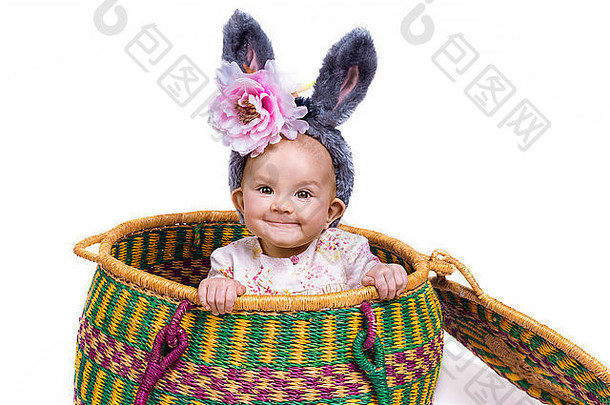 有趣的婴儿戴着兔子耳朵坐在篮子里