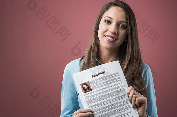 一个年轻的微笑着的女人拿着她的简历正在申请一份工作