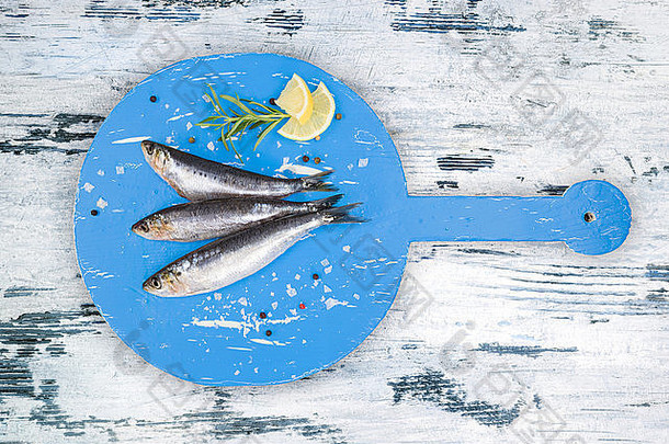 新鲜的鳀鱼鱼轮蓝色的木厨房董事会白色蓝色的木表格前视图烹饪海鲜概念