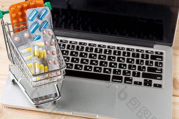 迷你购物车，开放式笔记本电脑上有药丸泡罩包装。网上商店的概念