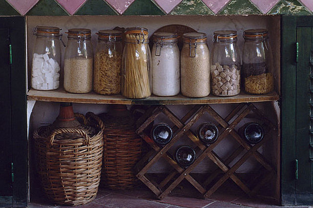 米饭和意大利面放在<strong>酒架</strong>上方的乡村木架上的玻璃储物罐中