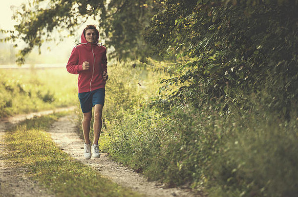 年轻人一边沿着乡村公路慢跑，一边享受健康的生活方式、锻炼和健身理念
