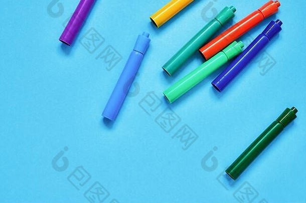 蓝色背景上的彩色毛毡笔，可放置文字。俯视图，空间。回到学校的概念。