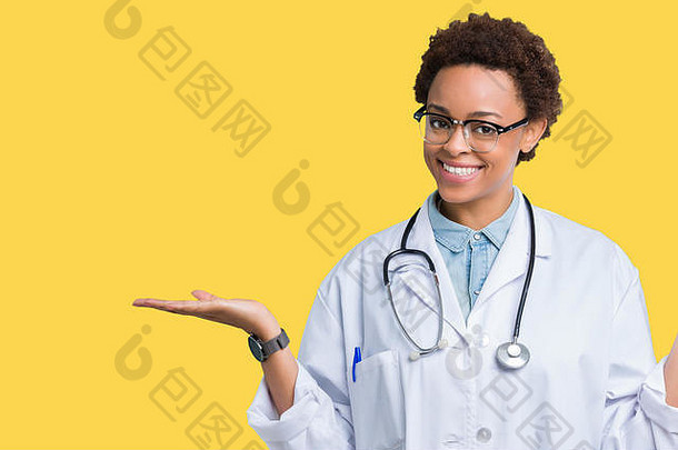 年轻的非裔美国女医生，穿着医用外套，在孤立的背景下微笑着，双手张开手掌，展示和广告公司
