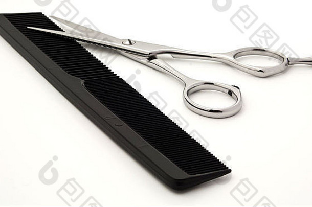 银光闪闪的剪发剪刀或剪刀和黑色梳子的特写镜头，在白色背景上隔离，留有复印空间。