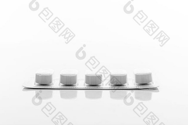 白色箔片胶囊片剂包装中的药丸平放，并在白色背景上隔离