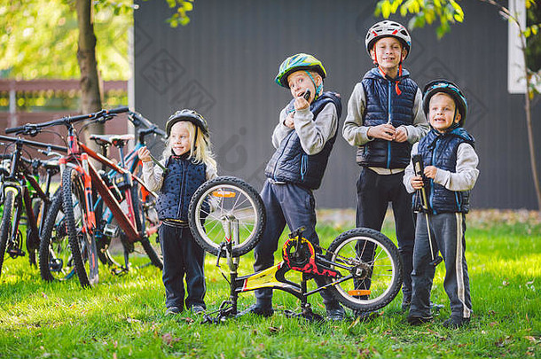 儿童力学，自行车修理。阳光明媚的日子里，快乐的孩子们一起在户外修理自行车。自行车维修概念。用工具摆姿势