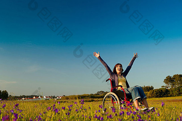 一位快乐的残疾妇女坐在绿色草地上的轮椅上