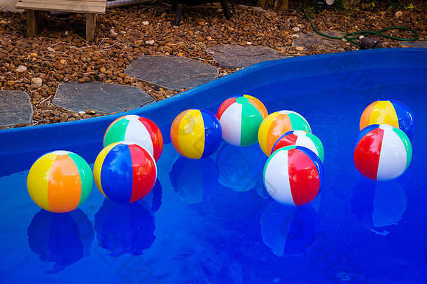 五颜六色的沙滩球漂浮在游泳池里。