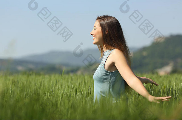 一个快乐的女人在麦田里行走的侧视图