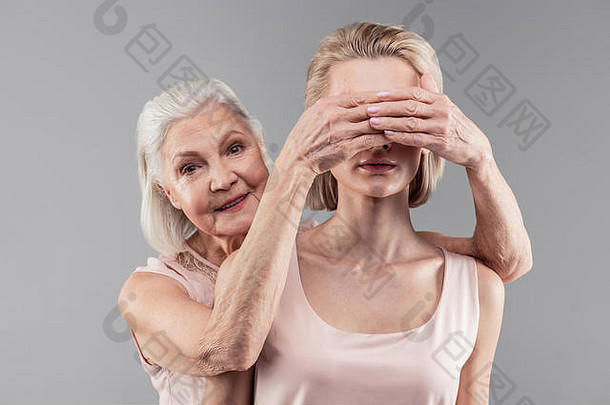 微笑着的可爱的老妇人遮住了她美丽女儿的眼睛