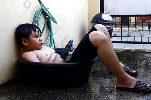 照片年轻的亚洲男孩冷却水盆地水软管临时搭建的淋浴击败夏天热