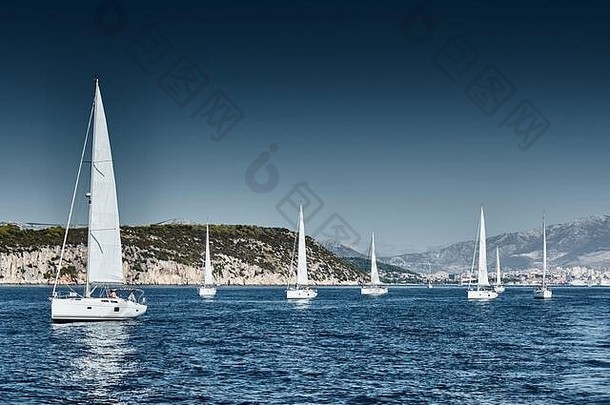 美丽的海景中有帆船，地平线上有帆船比赛，有帆船赛，竞争激烈，色彩鲜艳，岛上有风车