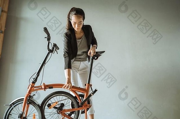 打开<strong>折叠自行车</strong>时，亚洲年轻女子站在客厅上