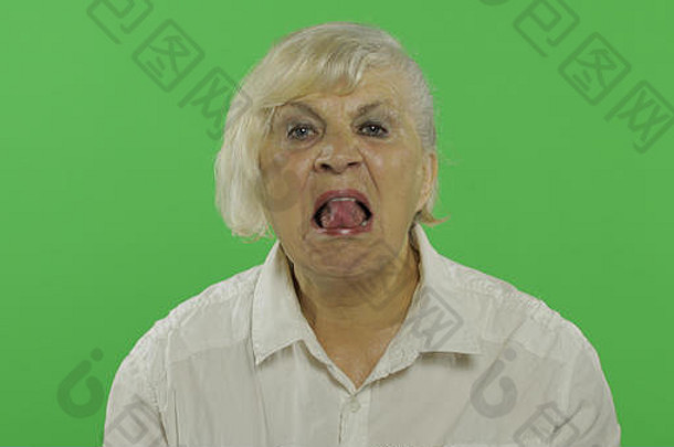 一位老妇人露出舌头。穿着白衬衫的快乐老奶奶。放置您的徽标或文字。色度键。绿色屏幕背景。情感概念