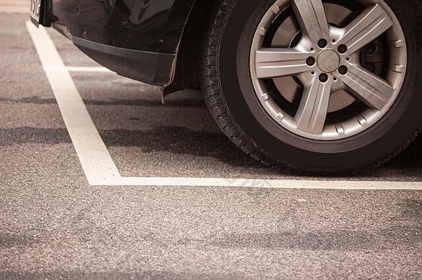 停车场沥青路面上白色斑点内停车场轮胎、车轮的特写镜头。