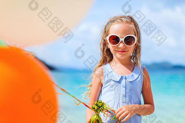 暑假期间，小女孩在海滩上玩彩色气球