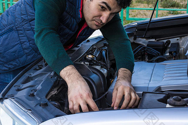 一位西班牙裔男子正午在室外停车场修车的特写镜头。紧急服务。