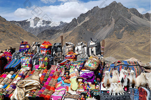 五颜六色的秘鲁手工艺品展出，背景是一座令人印象深刻的山。秘鲁拉亚