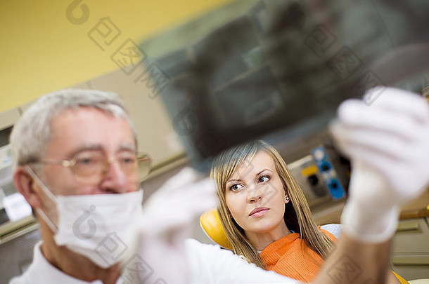 牙医正在给他的病人看牙齿的x光片