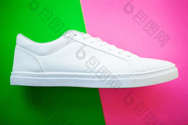 一双绿色粉色背景的新款时尚白色运动鞋。