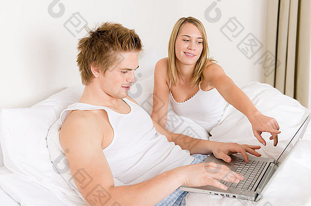 卧室-白色床上有笔记本电脑的年轻夫妇