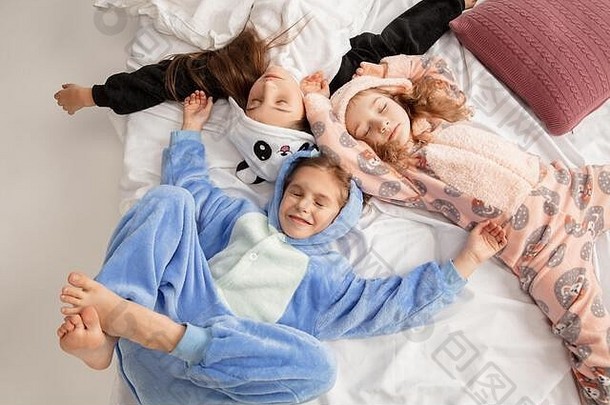 穿着色彩鲜艳的柔软温暖睡衣的孩子们在家里玩耍。小女孩们在一起玩，聚会，欢笑，玩耍，看起来很时髦，很快乐。童年观念，休闲活动，快乐。