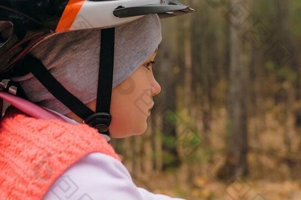 一名白人<strong>儿童</strong>在秋季公园骑自行车。小女孩在森林里骑着黑橙色的自行车。这孩子去做自行车运动。骑自行车的运动骑乘