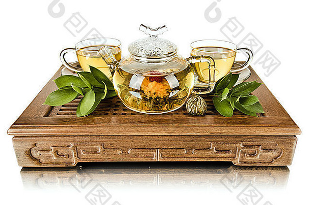 生活玻璃茶壶流绿色茶杯木三脚架白色背景孤立的茶仪式