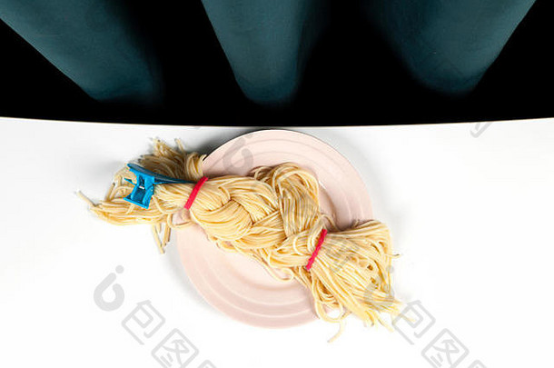 一顿美味的意大利黄油意大利面，装在粉红色盘子里，金色的辫子状头发。极简趣味和古怪的流行静物摄影