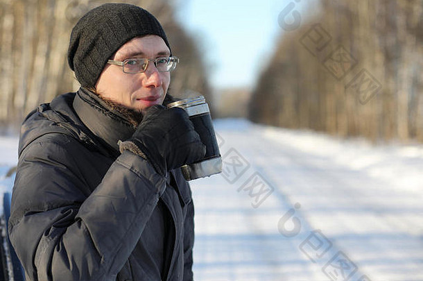 冬天，男人在户外用杯子喝热茶