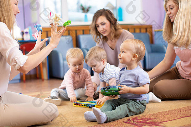 年轻的妈妈孩子们俱乐部婴儿玩音乐的玩具