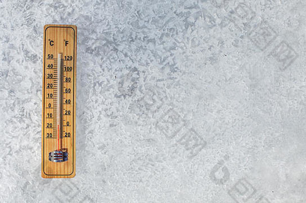 放在冰层上的温度计俯视图，显示温度低至-20摄氏度。极冷冰冻天气概念图