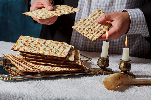 犹太男子正在为Matzah无酵面包祈福，而另一名身穿kippah头巾的男子则在为圣徒祈福时阅读Haggadah传统经文