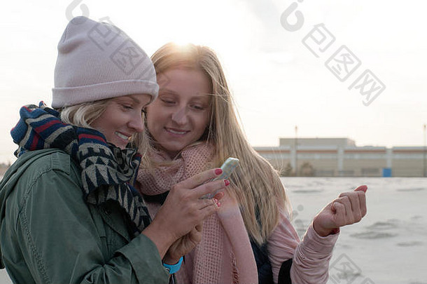 美女自拍。秋天，两名城市妇女在海滩上为自己拍照。
