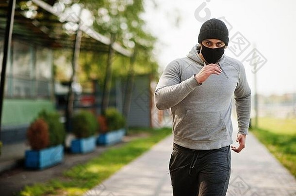 在冠状病毒隔离期间，一名戴黑色医用面罩的阿拉伯男子在户外奔跑。