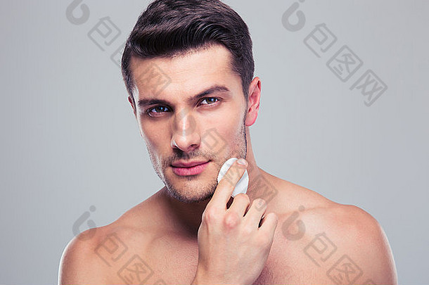 男人。清洁脸皮肤击球棉花垫灰色的背景