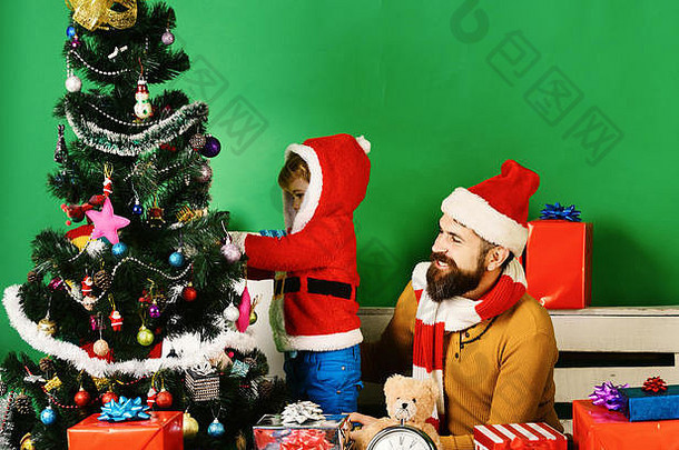 圣诞老人助理礼物盒子圣诞节家庭装修冷杉树绿色背景男孩男人。胡子快乐脸把圣诞节球树圣诞节装饰概念
