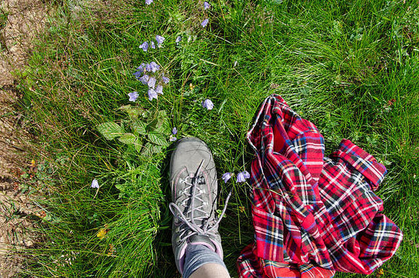 穿着<strong>登山鞋</strong>的腿踏上野花盛开的山野