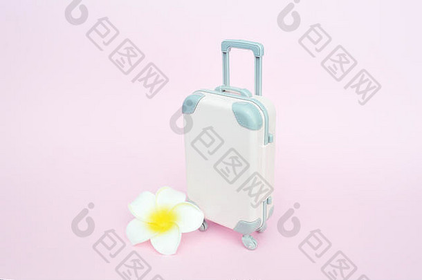 时尚的手提箱和粉色背景上的白色花朵，俯视图中有文字位置。旅游概念