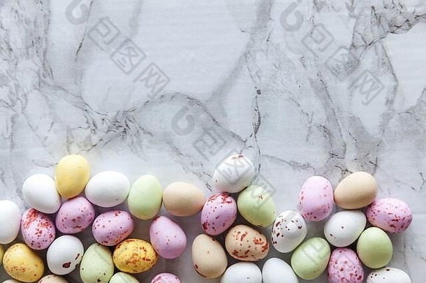 复活节快乐概念。为假期做准备。复活节彩色糖果巧克力蛋糖果，时尚的灰色大理石背景。简约简约型平面俯视空间
