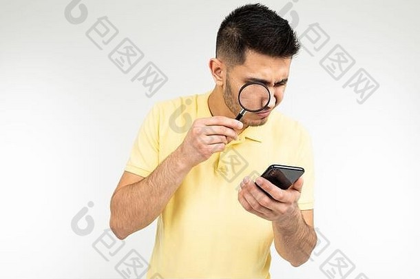 有<strong>近视眼</strong>的帅哥手里拿着放大镜和智能手机，背景是白色的，有复印空间